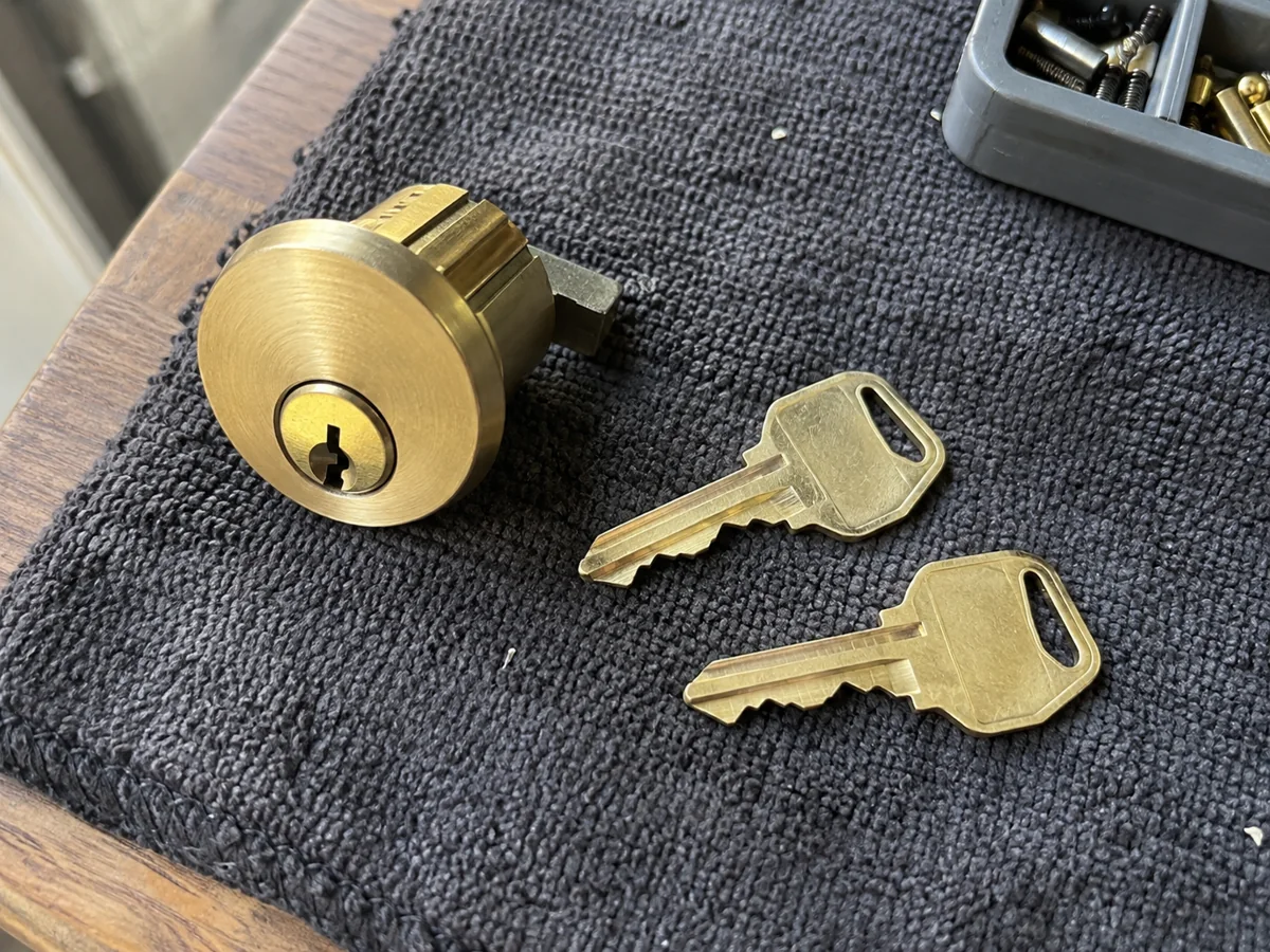 Brass cylinder with two house keys on a dark towel