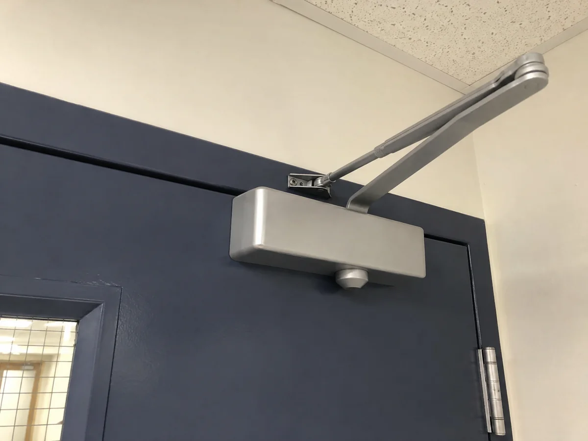 Silver overhead closer on a navy office door