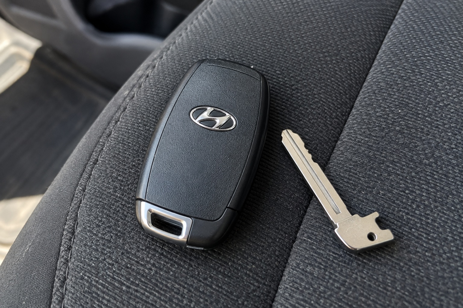 AI-generated illustration of a black key fob with a Hyundai emblem on a vehicle seat.